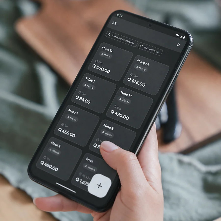 Celular en la mano con la pantalla de mesas de Altoque